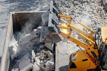 excavator throwing concrete material into a bin