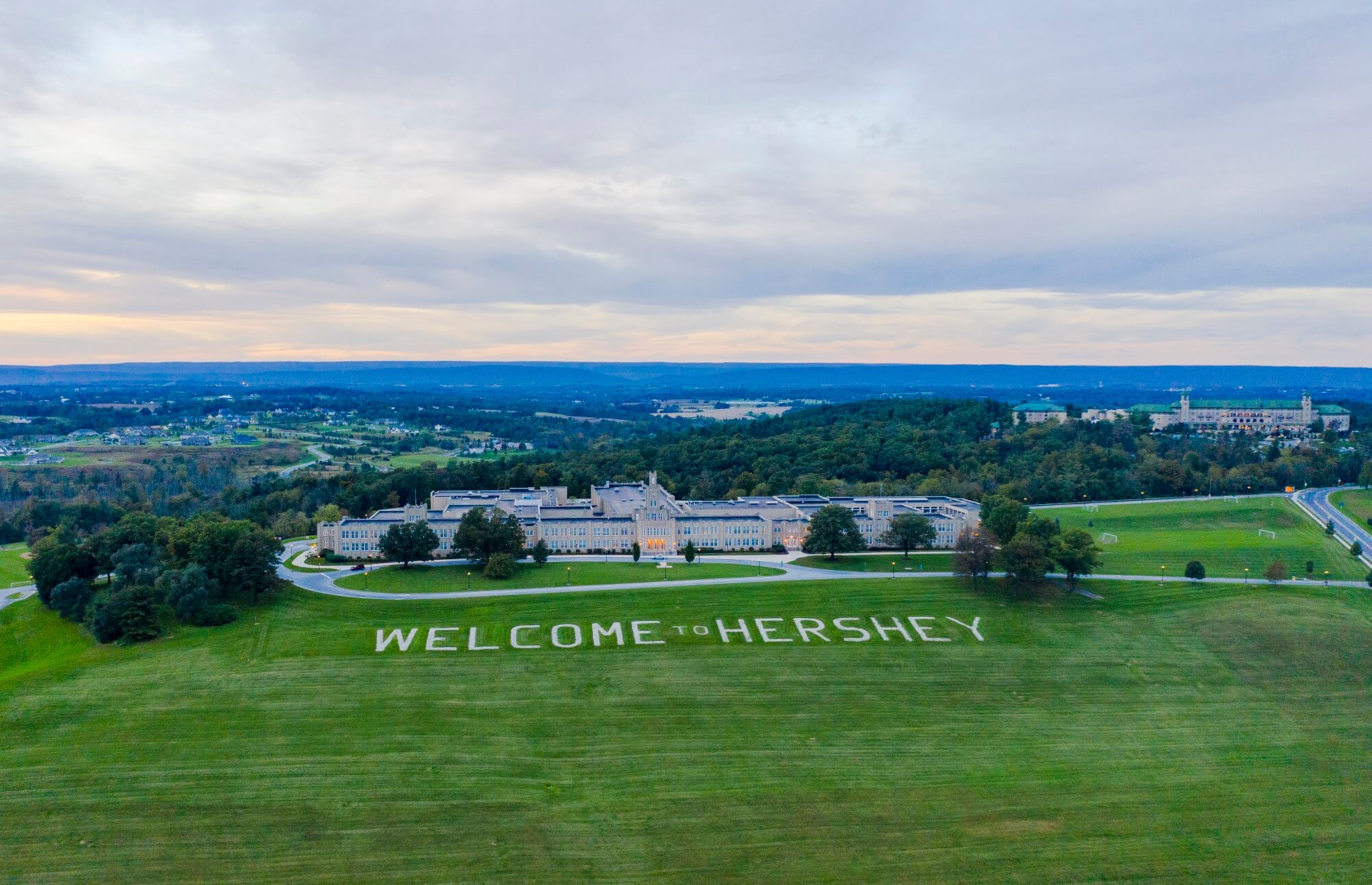 welcome to hershey sign on lawn with building behind