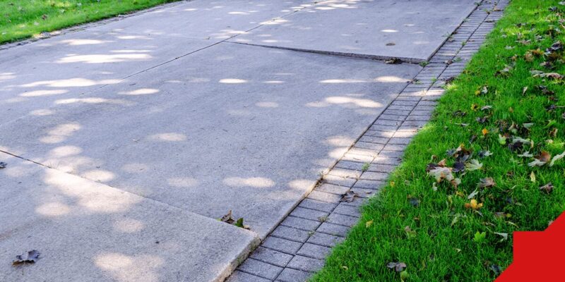 unleveled sidewalk surrounded by grass